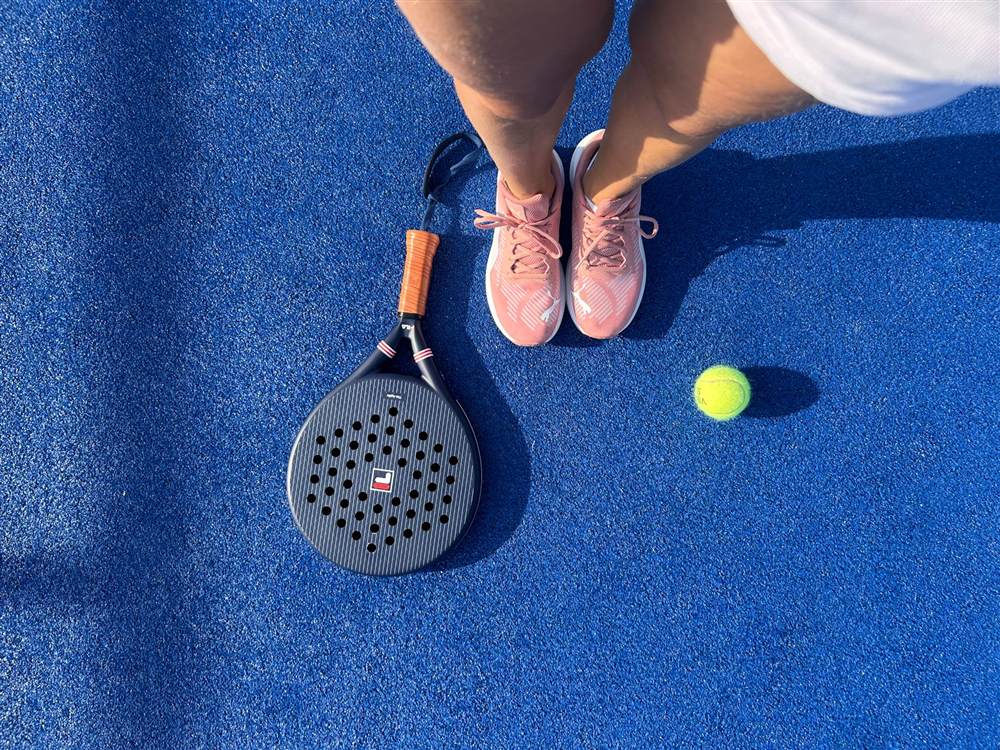 A padel racket and ball on a blue court